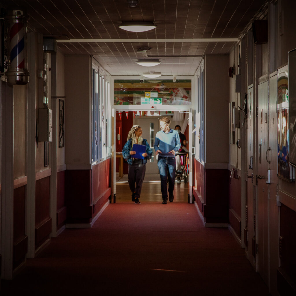 Two care workers walk along corridor